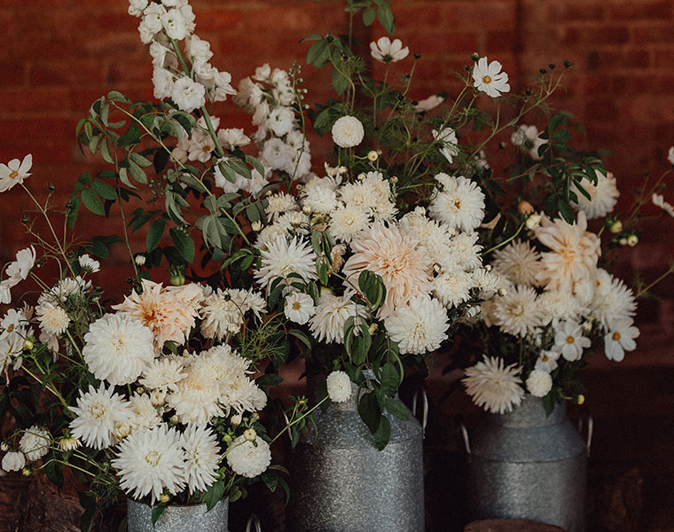 Autumn arrangement of cream flowers and greenery in a rustic urn