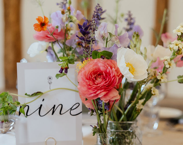 Pink rose and pastel flowers in a glass vase with wedding place card